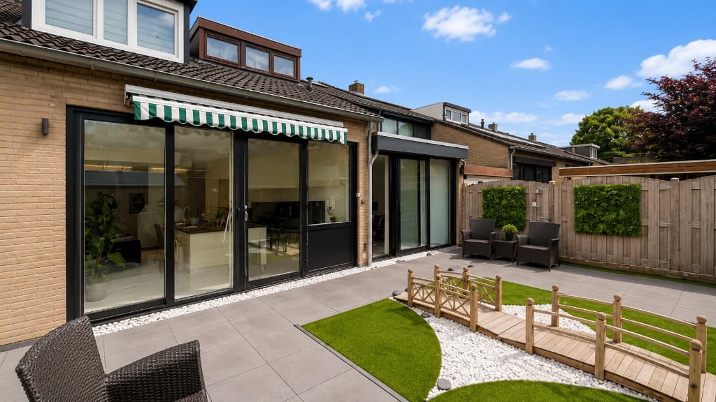 Woonkameruitbouw en vernieuwde tuin bij een bakstenen woning in Nederland, met terrasbestrating, tuindeuren en een afgewerkte achtertuin.