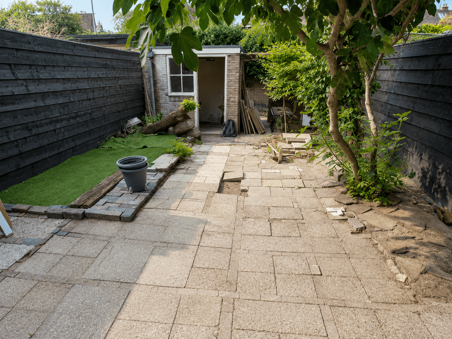 Versleten en begroeide bestrating vóór de heraanleg van de tuin.