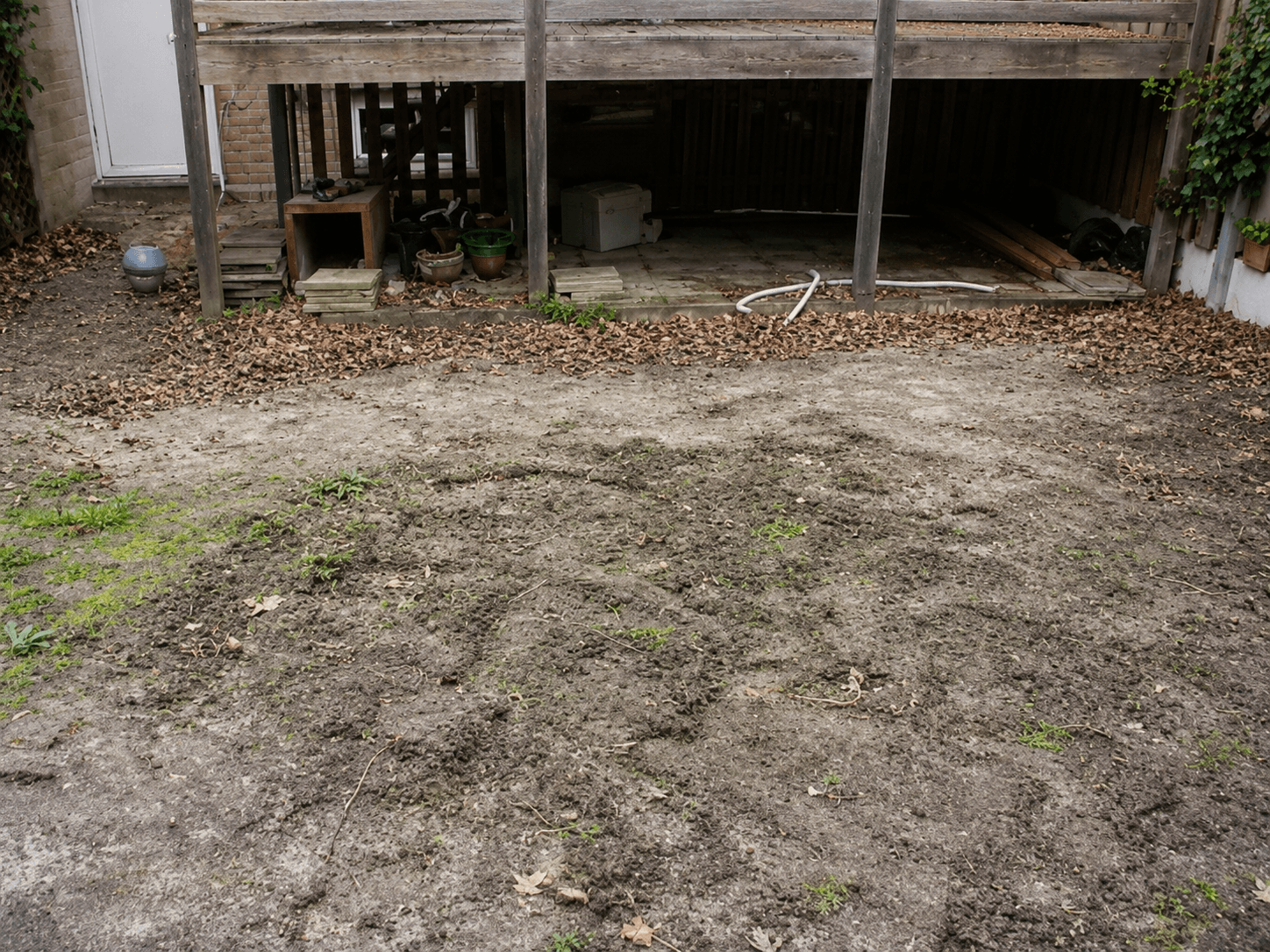 Geëgaliseerde ondergrond in de achtertuin, voorbereid voor kunstgras en bestrating.